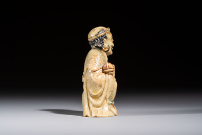 A Chinese gilt-polychromed soapstone Luohan on a wooden stand, 19th C.