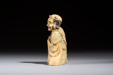 A Chinese gilt-polychromed soapstone Luohan on a wooden stand, 19th C.
