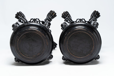 A pair of black-lacquered carved wood chinoiserie stands on lion feet, 19th C.