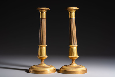 A pair of Empire parcel-gilt bronze candlesticks, early 19th C.