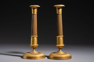 A pair of Empire parcel-gilt bronze candlesticks, early 19th C.