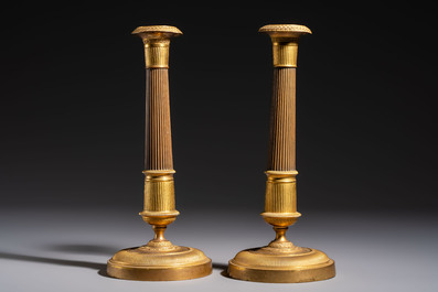 A pair of Empire parcel-gilt bronze candlesticks, early 19th C.