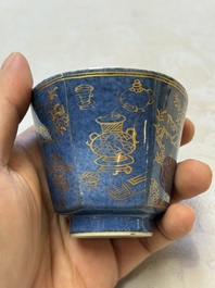 A pair of Chinese gilt-decorated powder-blue-ground 'Antiquities' cups and saucers, lingzhi mark, Kangxi