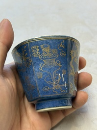 A pair of Chinese gilt-decorated powder-blue-ground 'Antiquities' cups and saucers, lingzhi mark, Kangxi
