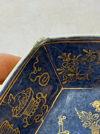 A pair of Chinese gilt-decorated powder-blue-ground 'Antiquities' cups and saucers, lingzhi mark, Kangxi