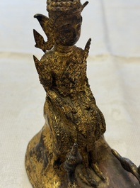 A Thai gilt-bronze figure of a seated deity with attendant animals, 19th C.