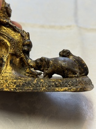 A Thai gilt-bronze figure of a seated deity with attendant animals, 19th C.