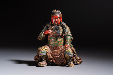 A Chinese gilt and polychrome lacquered papier-m&acirc;ch&eacute; and wooden Guandi on a wooden stand, 19th C.