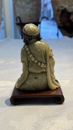 A Chinese gilt-polychromed soapstone Luohan on a wooden stand, 19th C.