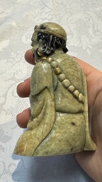 A Chinese gilt-polychromed soapstone Luohan on a wooden stand, 19th C.