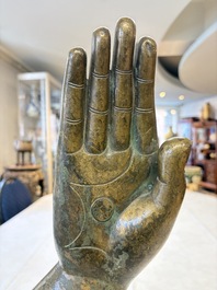 A rare and large Tibetan bronze forearm of a Buddhist figure with a chakra design, on a later metal stand, Qing