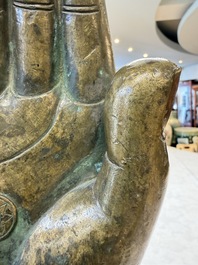A rare and large Tibetan bronze forearm of a Buddhist figure with a chakra design, on a later metal stand, Qing