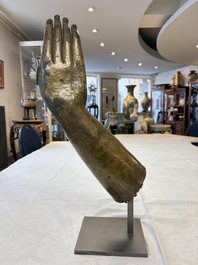 A rare and large Tibetan bronze forearm of a Buddhist figure with a chakra design, on a later metal stand, Qing