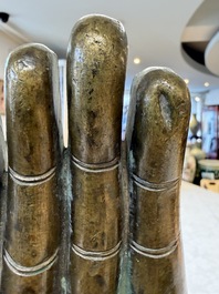 A rare and large Tibetan bronze forearm of a Buddhist figure with a chakra design, on a later metal stand, Qing