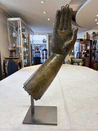 A rare and large Tibetan bronze forearm of a Buddhist figure with a chakra design, on a later metal stand, Qing