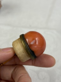 A Chinese gilt-decorated iron-red 'Buddhist Lions' snuff bottle with a red coral stopper, Buddhist Lion mark, Republic