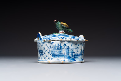 A blue and white Dutch Delft butter tub with a polychrome bird-shaped finial, 18th C.