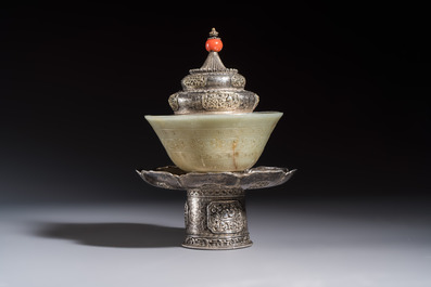 A Tibetan ritual jade bowl with a red coral-mounted silver cover and a stand, 19th C.