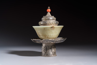 A Tibetan ritual jade bowl with a red coral-mounted silver cover and a stand, 19th C.