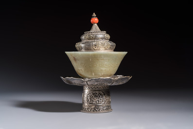 A Tibetan ritual jade bowl with a red coral-mounted silver cover and a stand, 19th C.