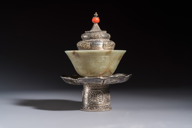 A Tibetan ritual jade bowl with a red coral-mounted silver cover and a stand, 19th C.