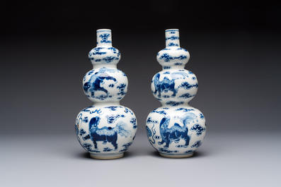 A pair of Chinese blue and white 'Buddhist Lions' triple gourd vases on reticulated wooden stands, 19th C.