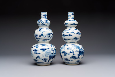 A pair of Chinese blue and white 'Buddhist Lions' triple gourd vases on reticulated wooden stands, 19th C.