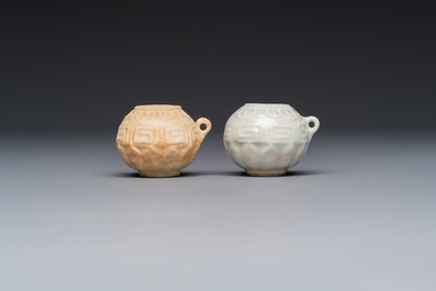 A pair of Chinese bird feeders with moulded design, one unglazed, on later wooden stands, Song