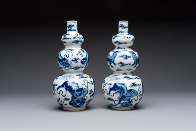 A pair of Chinese blue and white 'Buddhist Lions' triple gourd vases on reticulated wooden stands, 19th C.