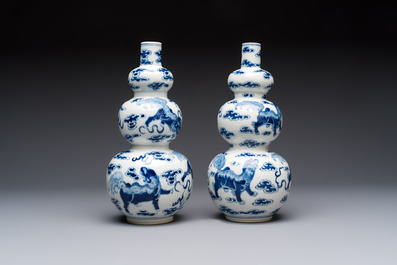 A pair of Chinese blue and white 'Buddhist Lions' triple gourd vases on reticulated wooden stands, 19th C.