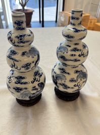 A pair of Chinese blue and white 'Buddhist Lions' triple gourd vases on reticulated wooden stands, 19th C.