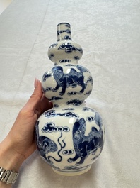 A pair of Chinese blue and white 'Buddhist Lions' triple gourd vases on reticulated wooden stands, 19th C.
