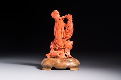 A Chinese carved red coral 'Goddess and Boys' group on a wooden stand, 19/20th C.