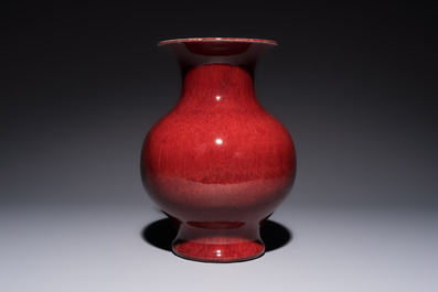A Chinese copper-red-glazed vase on a wooden stand, 20th C.