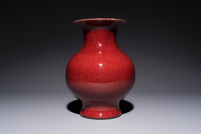 A Chinese copper-red-glazed vase on a wooden stand, 20th C.