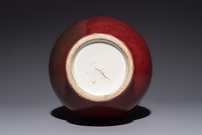 A Chinese copper-red-glazed vase on a wooden stand, 20th C.