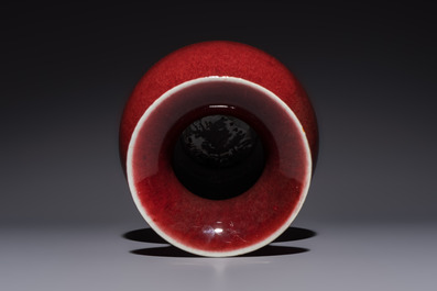 A Chinese copper-red-glazed vase on a wooden stand, 20th C.
