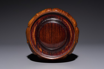 A Chinese copper-red-glazed vase on a wooden stand, 20th C.