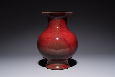 A Chinese copper-red-glazed vase on a wooden stand, 20th C.
