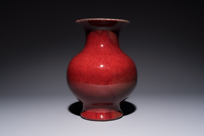 A Chinese copper-red-glazed vase on a wooden stand, 20th C.