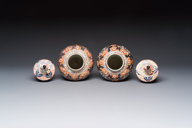 A pair of Japanese Imari baluster vases and covers on wooden stands, Edo, 18th C.