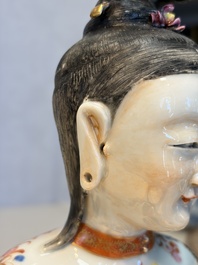 A Chinese famille rose candle holder in the shape of a court lady holding a 'Gu' vase, Qianlong