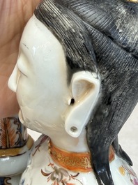 A Chinese famille rose candle holder in the shape of a court lady holding a 'Gu' vase, Qianlong