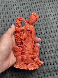 A Chinese carved red coral 'Goddess and Boys' group on a wooden stand, 19/20th C.