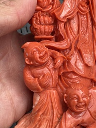 A Chinese carved red coral 'Goddess and Boys' group on a wooden stand, 19/20th C.