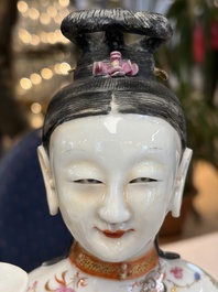 A Chinese famille rose candle holder in the shape of a court lady holding a 'Gu' vase, Qianlong