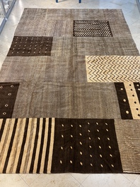 A large Persian hand-knotted woollen carpet with a geometric patchwork design, 20th C.