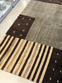 A large Persian hand-knotted woollen carpet with a geometric patchwork design, 20th C.