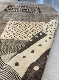 A large Persian hand-knotted woollen carpet with a geometric patchwork design, 20th C.