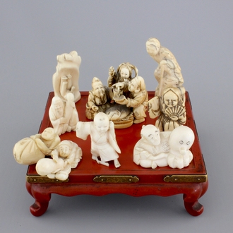 A set of 9 small Japanese ivory carvings, incl. netsuke, on a small red lacquer table, 19th/early 20th C.
